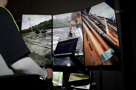 무인 굴착기를 사용자가 원격조종 스테이션에 앉아 조종하고 있는 모습. HD현대사이트솔루션 제공